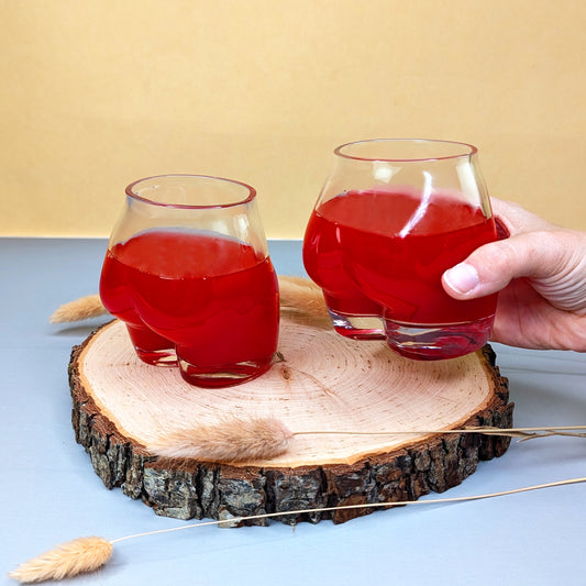 Hand greift nach einem gefüllten Glas, zweites Glas daneben auf Holzscheibe