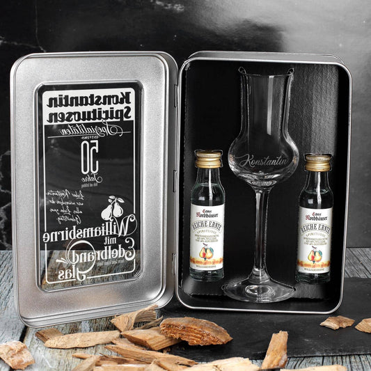 2 Flaschen Williamsbirne und ein bauchiges graviertes Edelbrandglas haben im Inneren der bedruckten Metallbox ausreichend Platz.