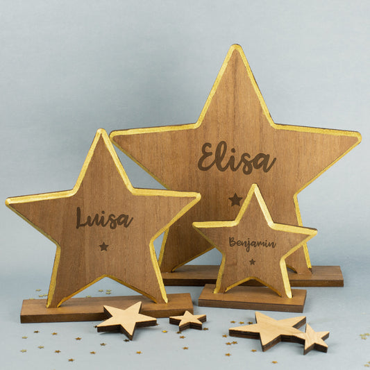 Detailansicht des gravierten Holzsterns in drei Größen mit goldfarbenem Rand, klar erkennbarer Schriftzug und kleinem Sternsymbol unter dem Namen.