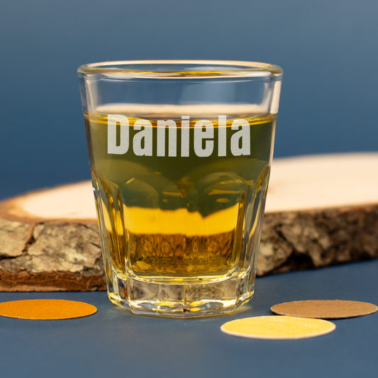 Personalisiertes Leonardo Schnapsglas mit Gravur Daniela und Holzdeko im Hintergrund