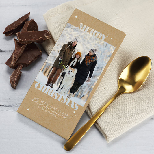 Weihnachtliche Schokolade mit personalisierter Verpackung und integriertem Foto. Die Tafel zeigt eine Familie beim winterlichen Spaziergang mit Hund, kombiniert mit dem festlichen Schriftzug „Merry Christmas“. Das Design wirkt edel und natürlich durch den Kraftpapier-Look und den dezenten Sternenaufdruck. Ideal als kleines Geschenk oder Wichtelidee für die Adventszeit.