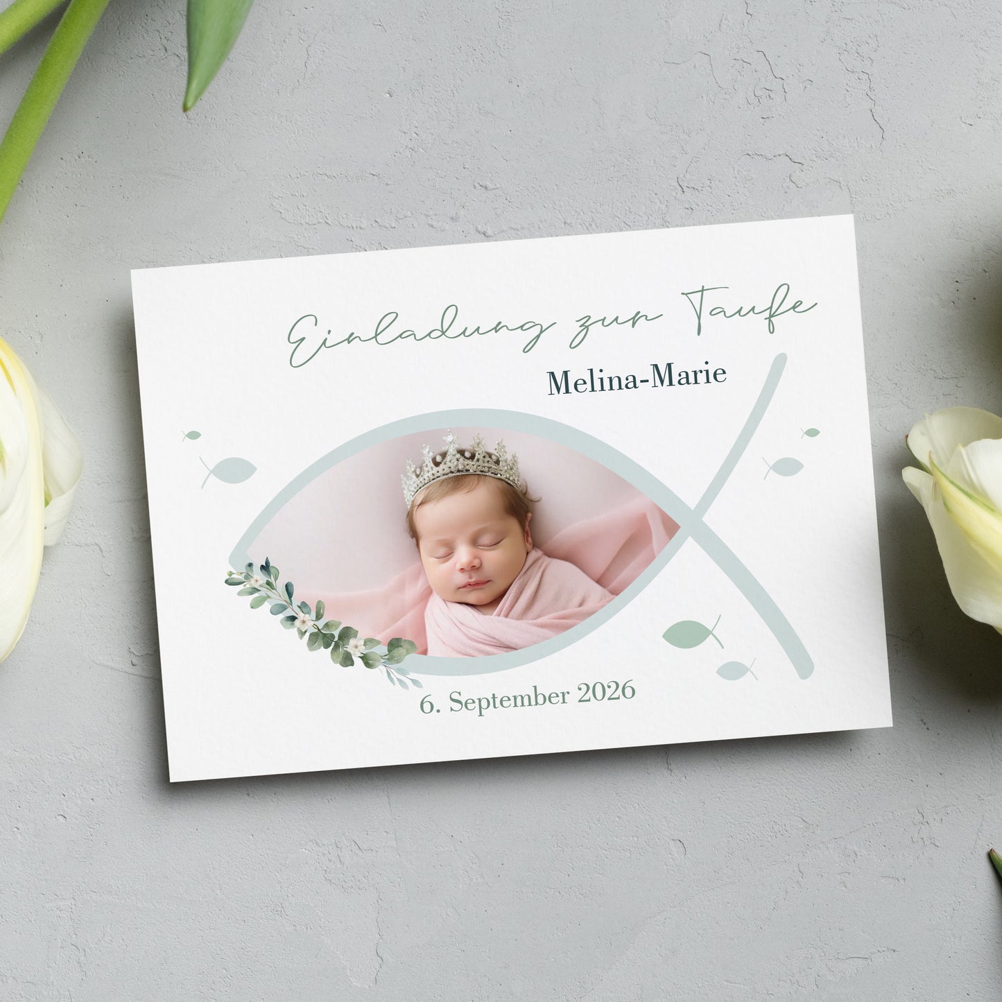 Einladungskarte zur Taufe mit christlichem Ichthys-Fischsymbol. Vorderseite mit personalisiertem Foto, sanften Grüntönen und liebevollen Blätterelementen. Hochwertiger Druck auf edlem Feinstpapier.