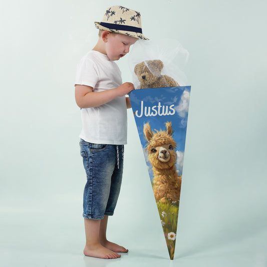 Junge mit Strohhut betrachtet eine Schultüte mit Alpaka-Motiv und dem Namen „Justus“