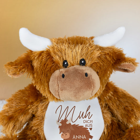 Nahaufnahme des Gesichts der Kuscheltier-Kuh mit weißen Hörnern, braunem Fell und sichtbarem Aufdruck „Muh dich aus“ mit Name Anna auf dem Bauch.