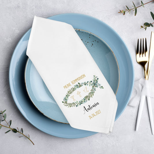 Personalisierte Stoffserviette zur Kommunion mit Fischmotiv und Eukalyptuskranz auf gedecktem Tisch mit blauem Geschirr