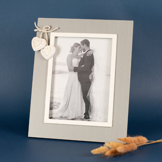 Grauer Bilderrahmen mit weißen Herzanhängern an der Ecke