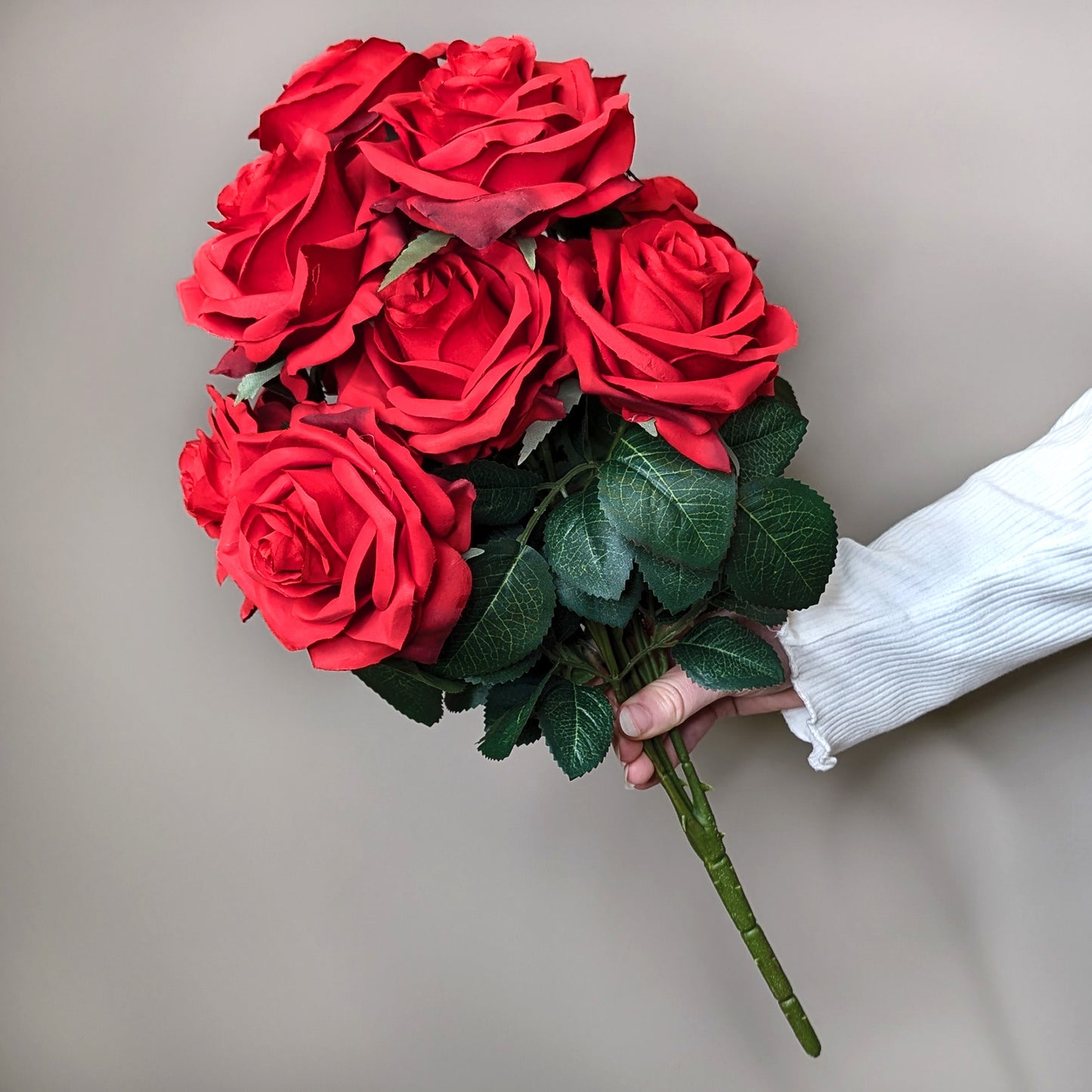 Roter Seidenrosenstrauß mit 10 Blüten in Hand gehalten, frontal