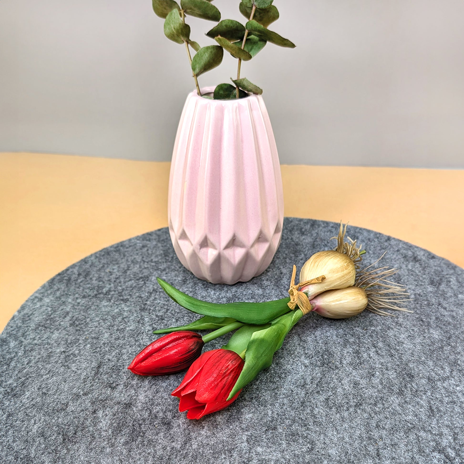 Tulpenbund mit roten Blüten und Zwiebeln neben einer Vase liegend