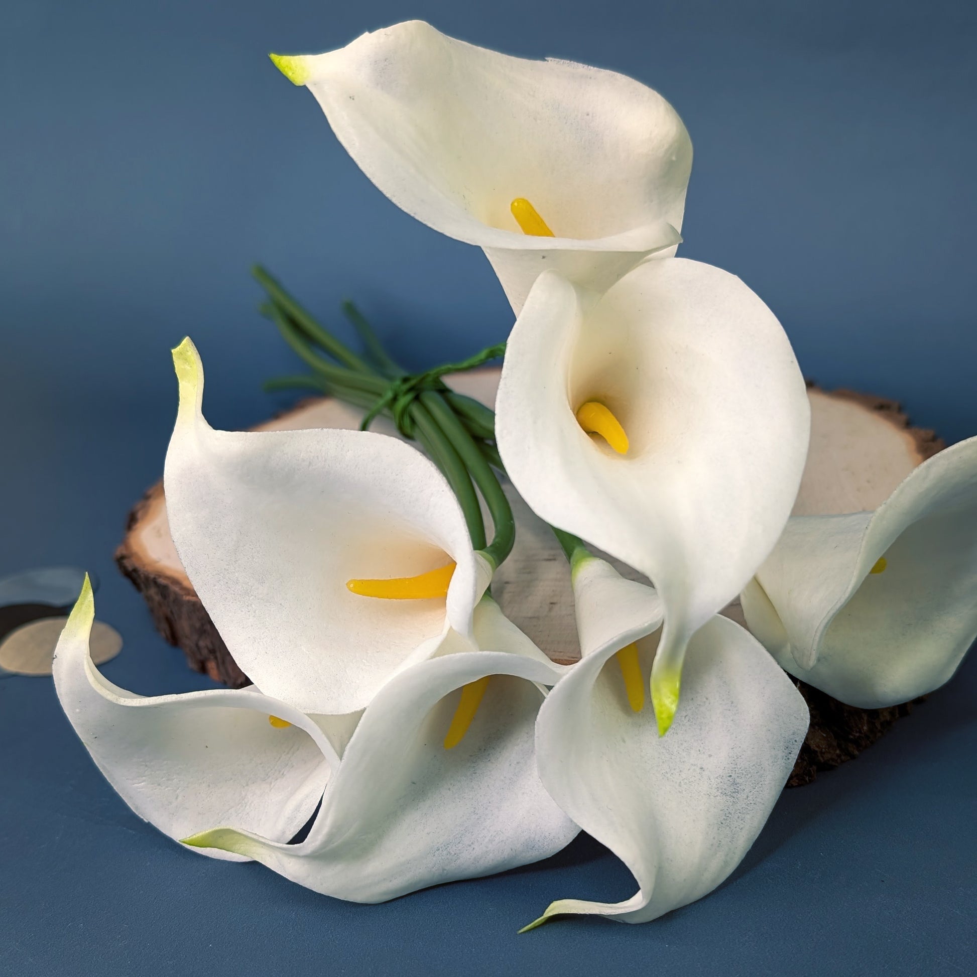 Künstlicher Calla-Strauß aus sieben Blüten auf Holzscheibe dekoriert