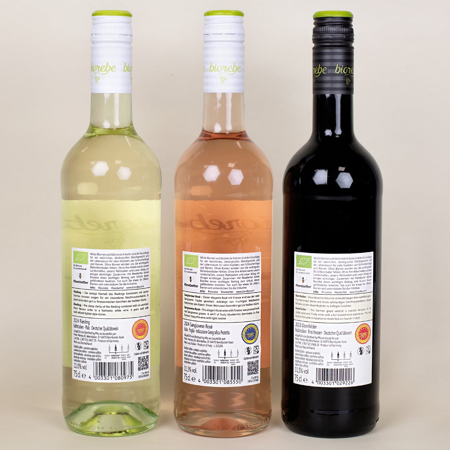 Drei Biorebe-Weinflaschen (Riesling, Sangiovese Rosé, Dornfelder) nebeneinander, Rückseiten-Etiketten mit Textangaben und QR-Codes.