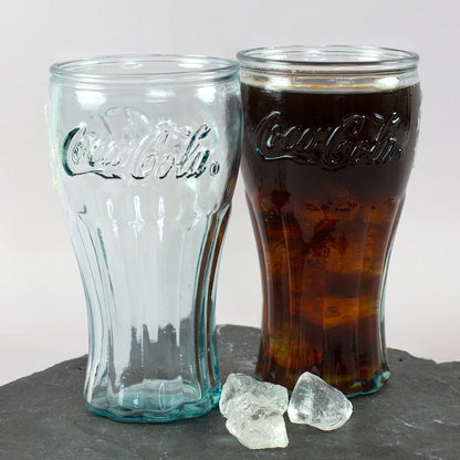 Retro Coca-Cola Glas aus 100 Prozent recyceltem Glas mit dunklem Getränk und leerem Glas auf Schieferplatte