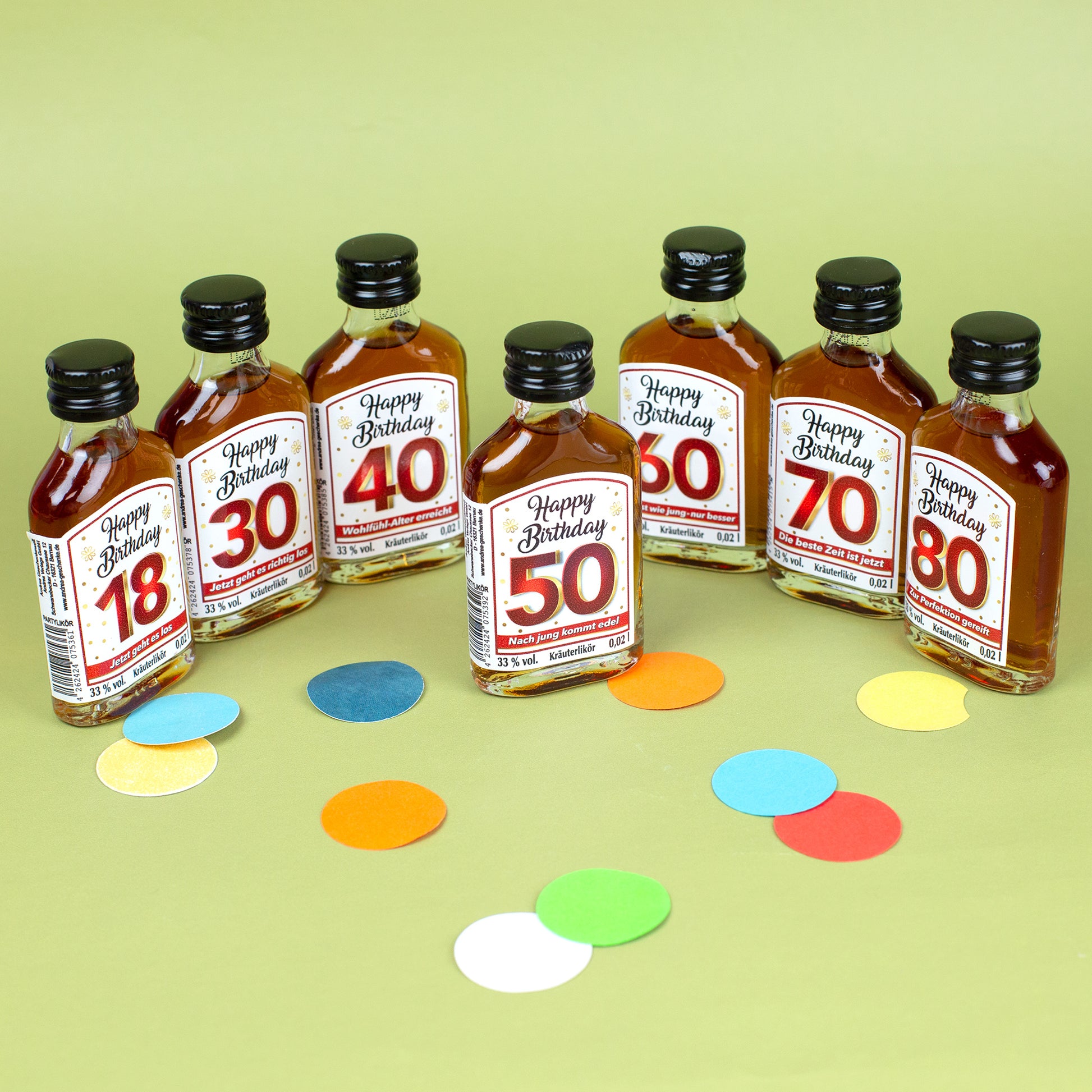 Set aus sechs Kräuterlikör-Miniaturen mit Etiketten für die Geburtstage 18, 30, 40, 50, 60, 70 und 80, buntes Konfetti auf dem Tisch