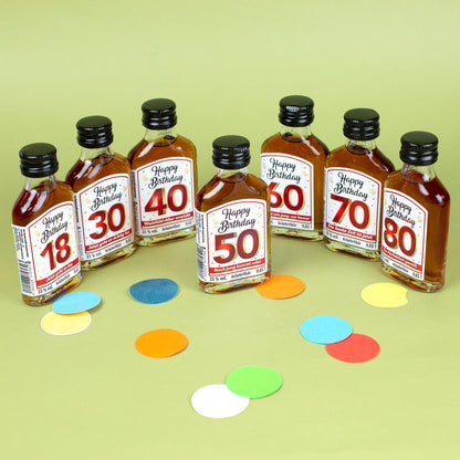 Set aus sechs Kräuterlikör-Miniaturen mit Etiketten für die Geburtstage 18, 30, 40, 50, 60, 70 und 80, buntes Konfetti auf dem Tisch