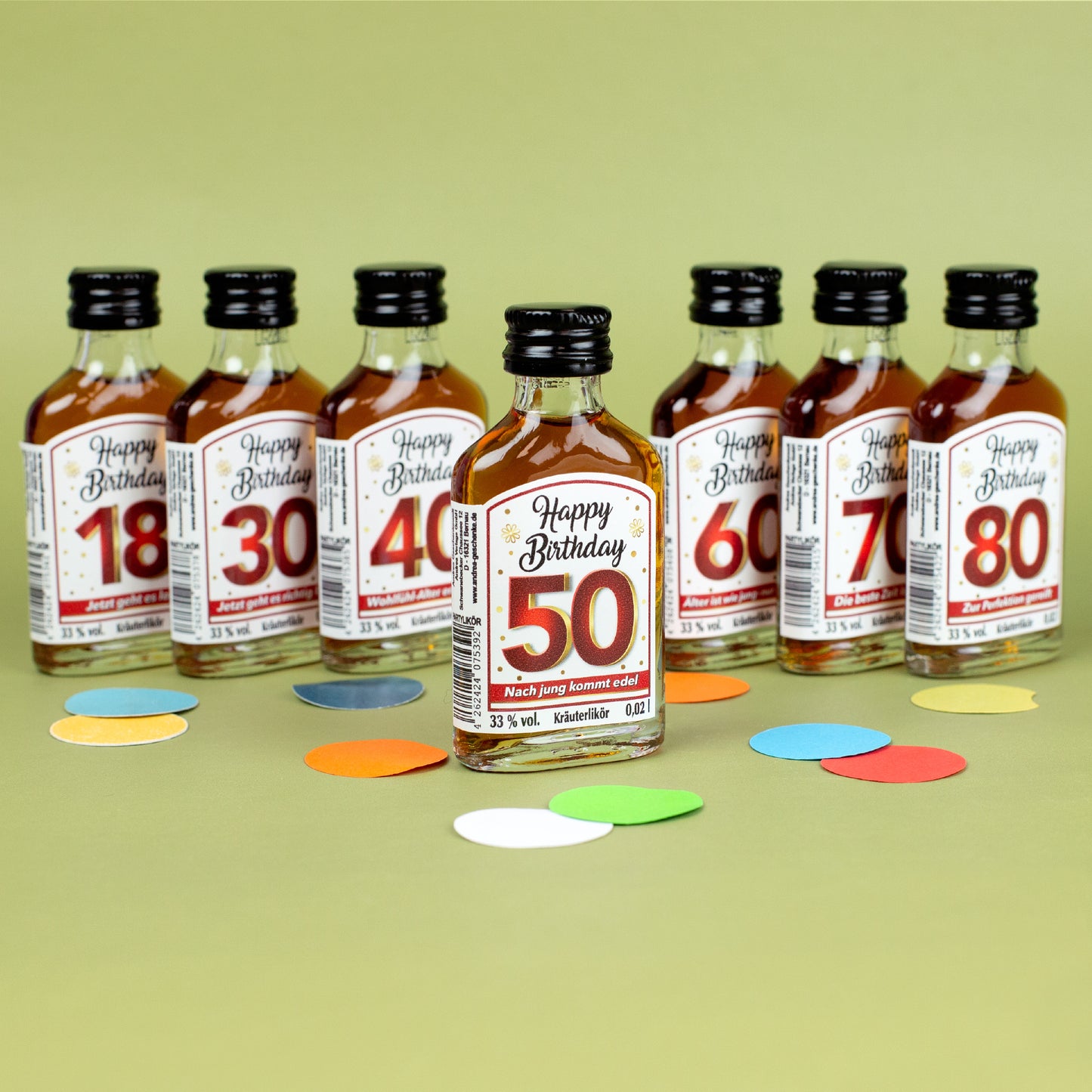 Kräuterlikör-Miniaturen „Happy Birthday“ als Set, vorne Flasche mit rotem Etikett „50 – Nach jung kommt edel“, dahinter weitere Jubiläumszahlen 18 bis 80