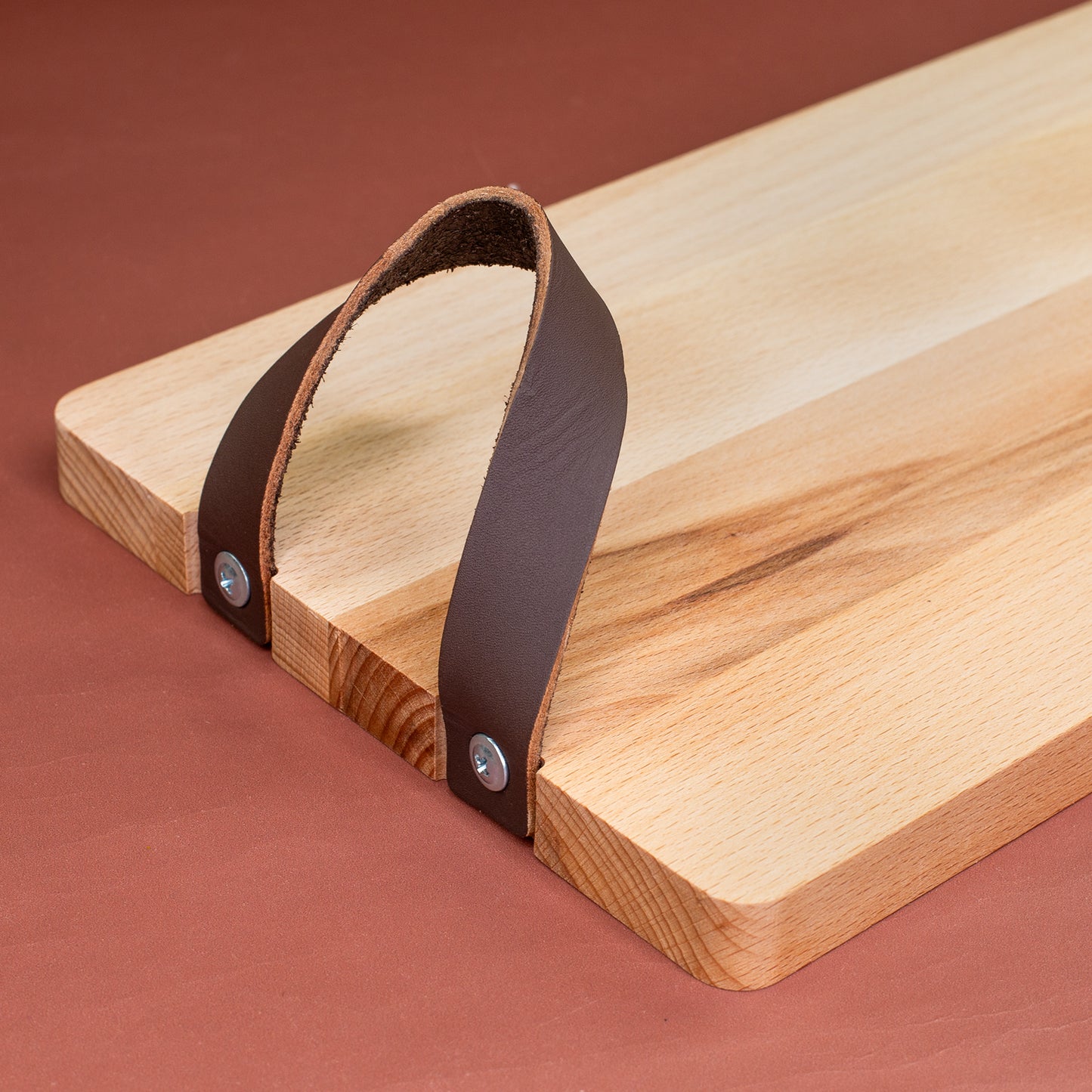 Detailaufnahme eines seitlich verschraubten Ledergriffs am Stollenbrett aus Buchenholz
