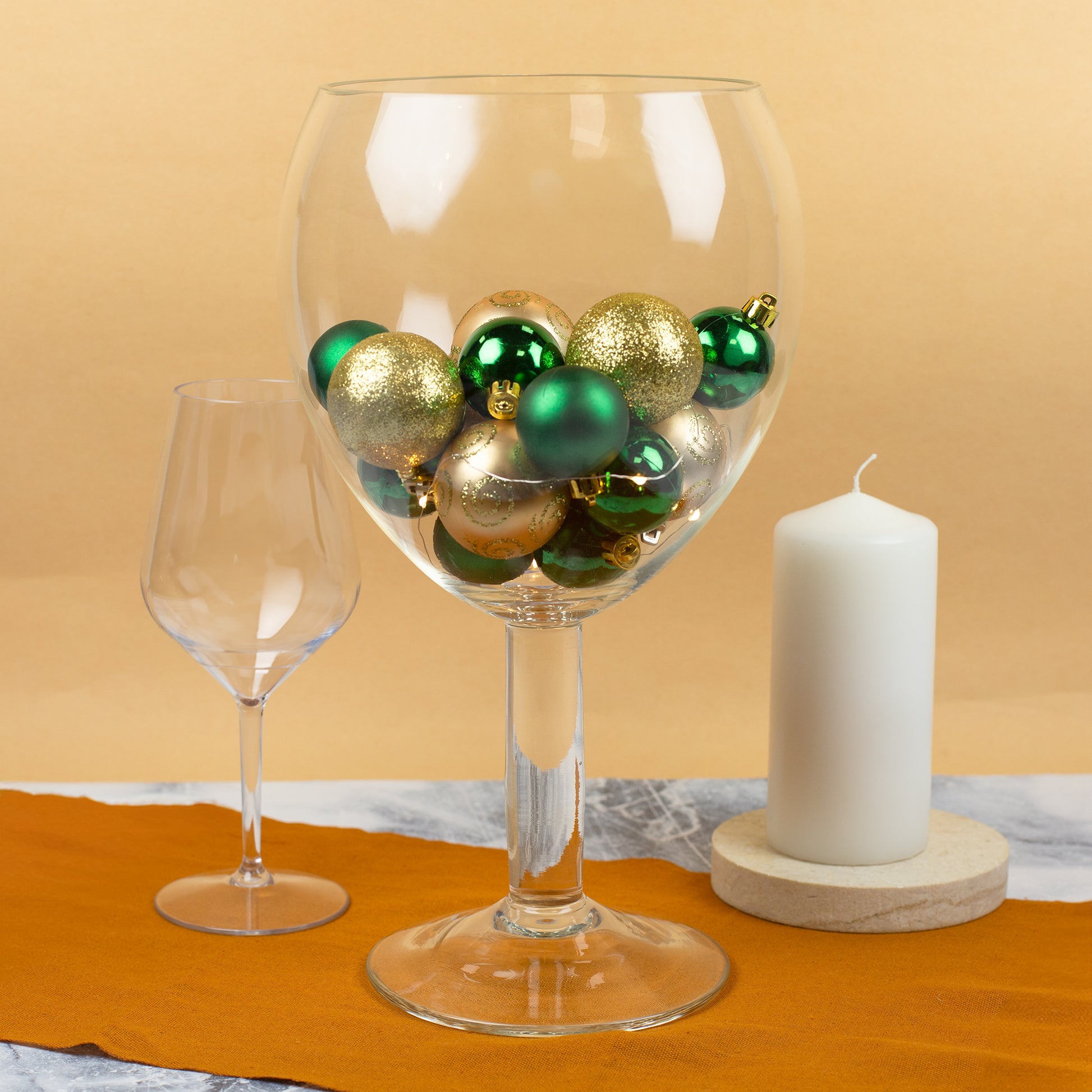 Riesengroßes Weinglas als Tischdeko mit gold-grünen Weihnachtskugeln gefüllt