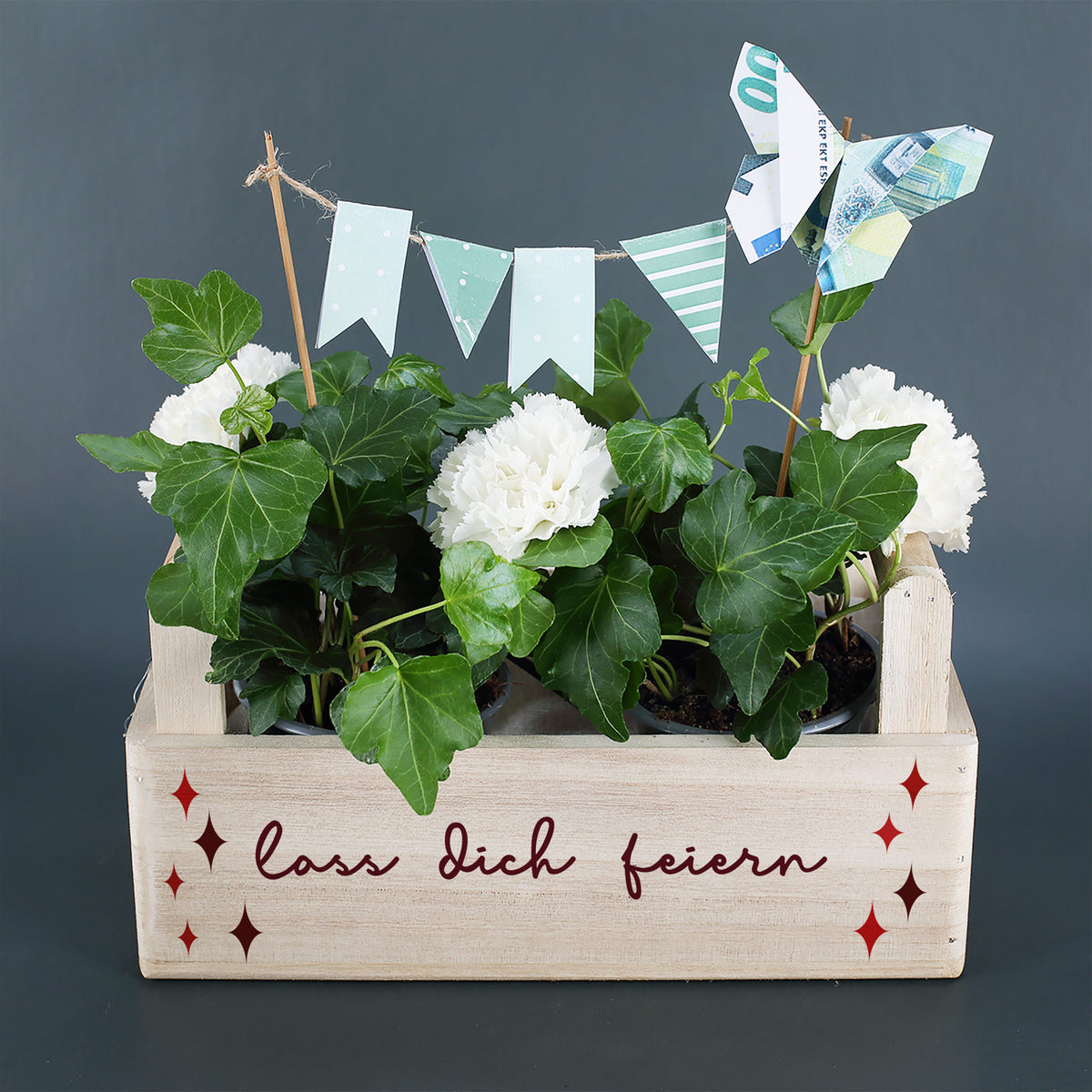 Geschenkkorb aus Holz mit weißen Blumen, Efeu, Geldgeschenk und Aufdruck „Lass dich feiern“