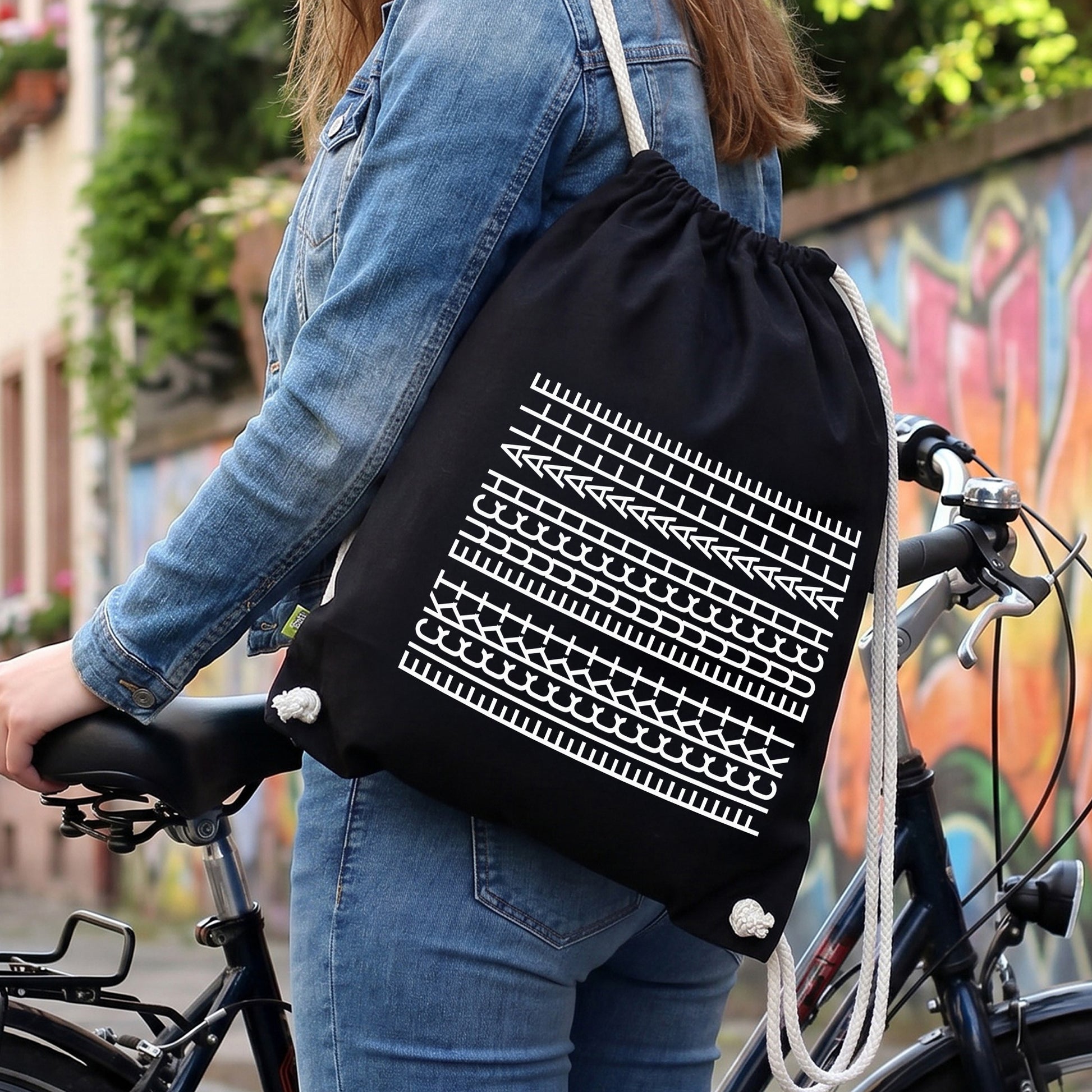 Schwarzer Turnbeutel mit weißem Muster-Motiv „F*ckt euch alle“ als Freizeitrucksack am Fahrrad getragen