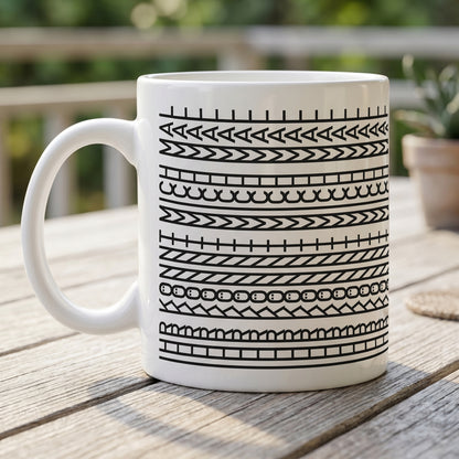 Weiße Tasse mit modernem Schwarz-Weiß-Muster auf einem Holztisch im Außenbereich