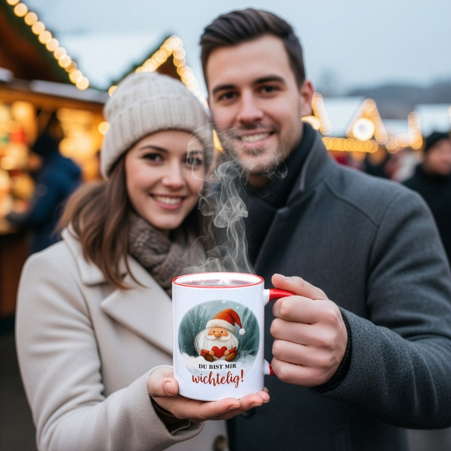 Paar auf Weihnachtsmarkt hält gemeinsam eine Tasse mit Wichtelmotiv und Spruch „Du bist mir wichtelig!“ – stimmungsvolles Geschenkfoto.