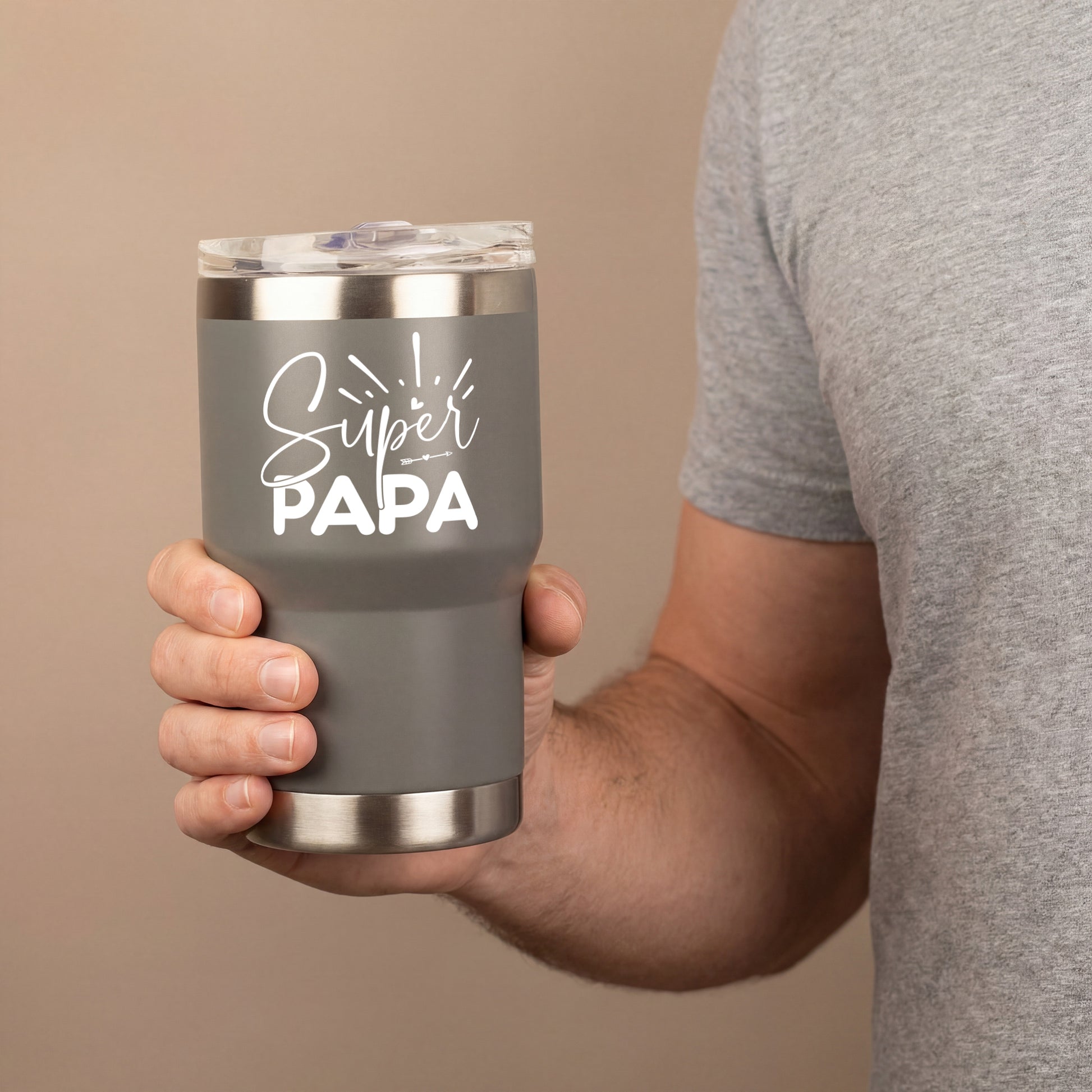 Grauer Thermobecher mit Super Papa Motiv in der Hand eines Mannes, doppelwandiger Becher mit transparentem Deckel