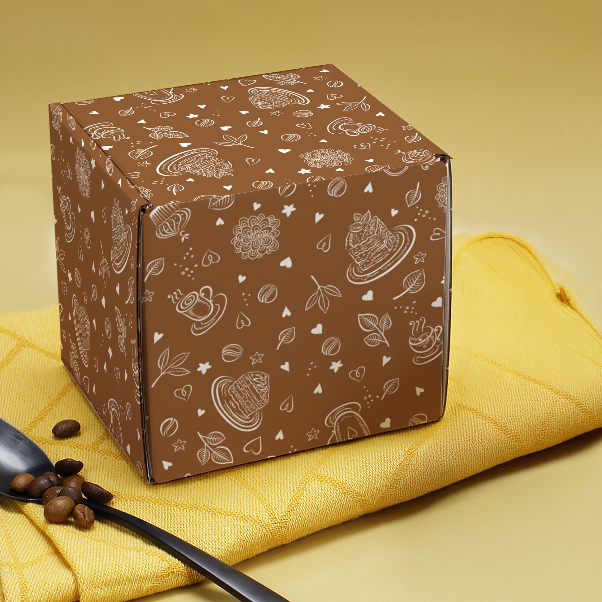 Braune Geschenkbox aus Pappe mit umlaufendem Kaffee-Motiv, frontal geschlossen dargestellt.