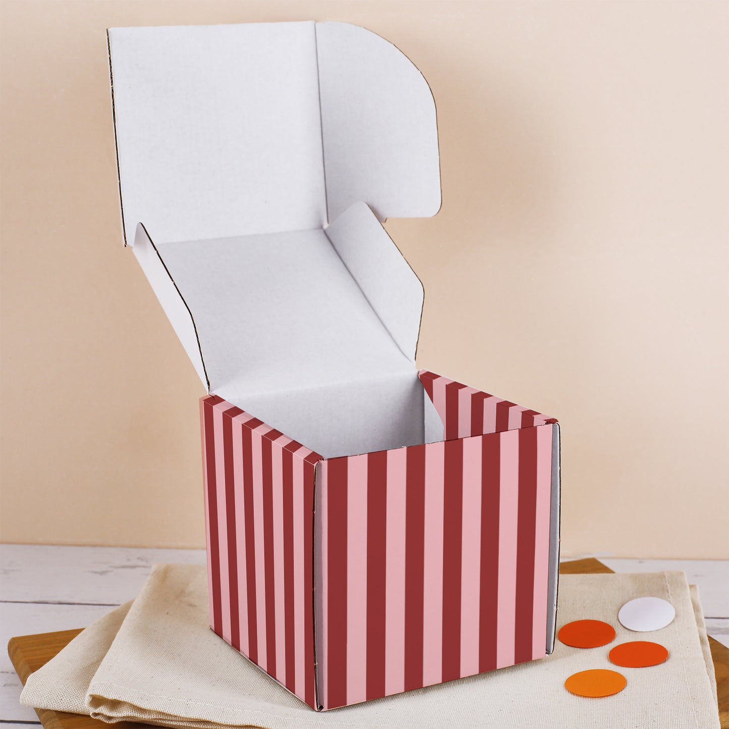 Geöffnete Geschenkbox zum Muttertag mit rosa-rotem Streifenmuster, leerem Innenraum und aufgeklapptem Deckel auf Stoffunterlage