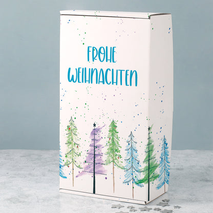 Weiße Geschenkbox zu Weihnachten mit aquarellartigen Tannenbäumen, Farbsprenkeln und blauem Frohe Weihnachten Schriftzug