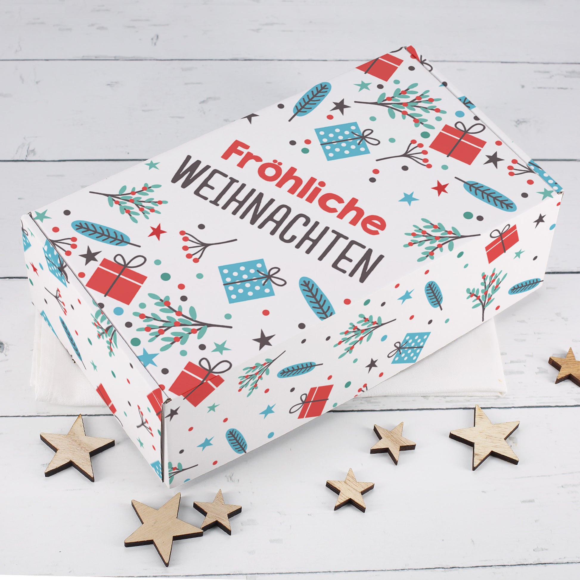 Weiße Geschenkbox zu Weihnachten mit Fröhliche Weihnachten Schriftzug, Geschenk Motiven, Zweigen, Sternen und Holzsternen als Dekoration