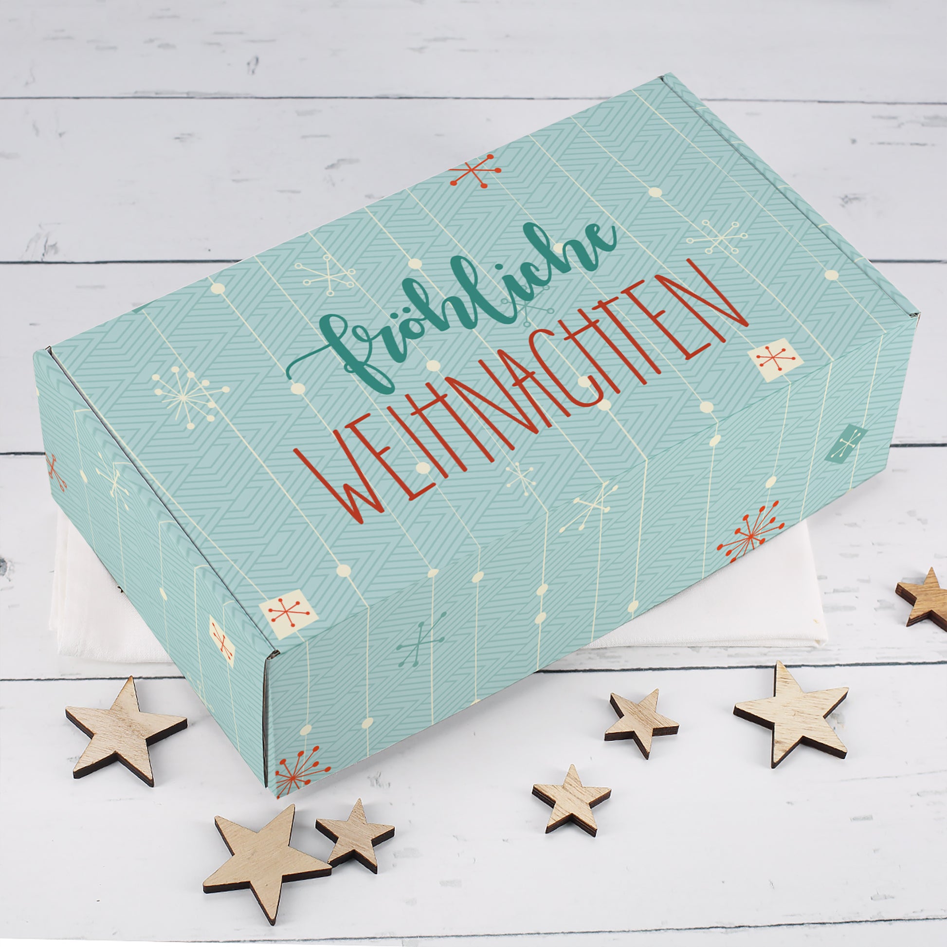 Türkise Geschenkbox zu Weihnachten mit grafischem Muster, roten Akzenten, Schneeflocken und Fröhliche Weihnachten Schriftzug