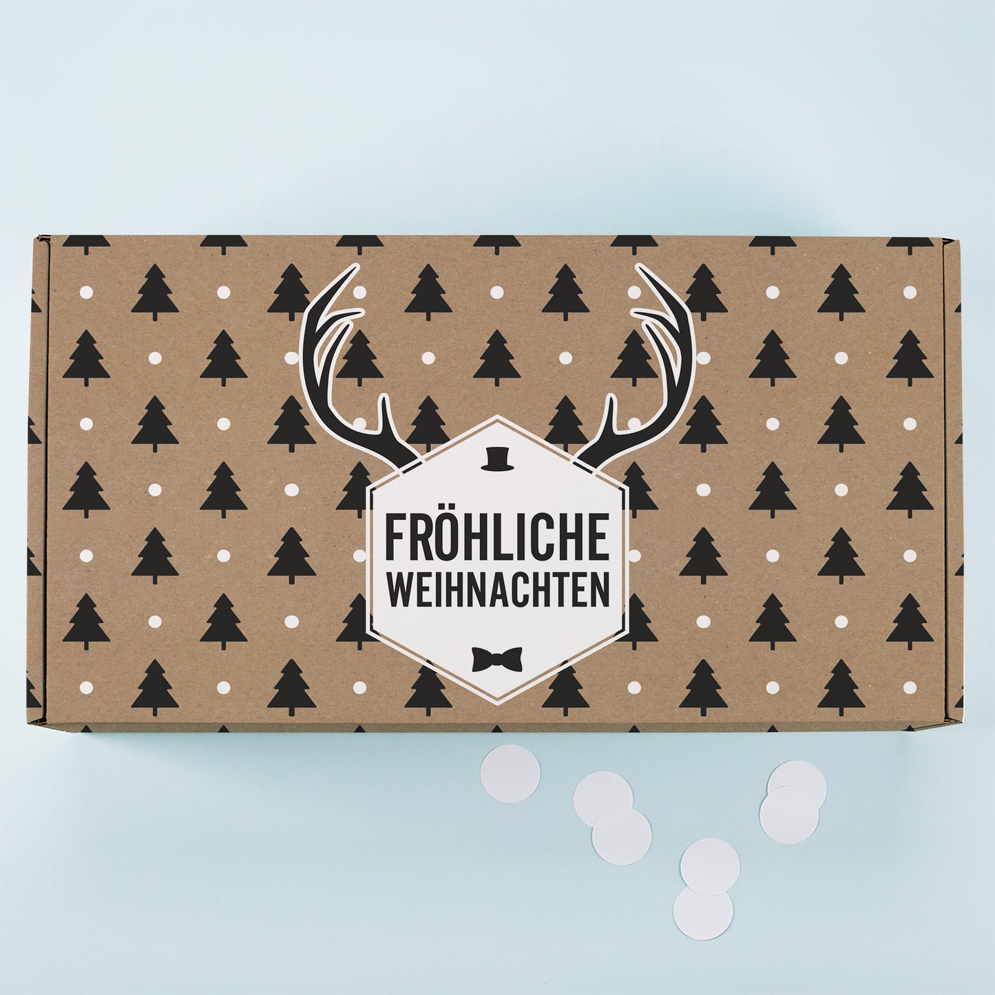Kraftpapier Geschenkbox von oben mit Tannenbaum Muster, weißen Punkten, Rentier Motiv und Fröhliche Weihnachten Schriftzug