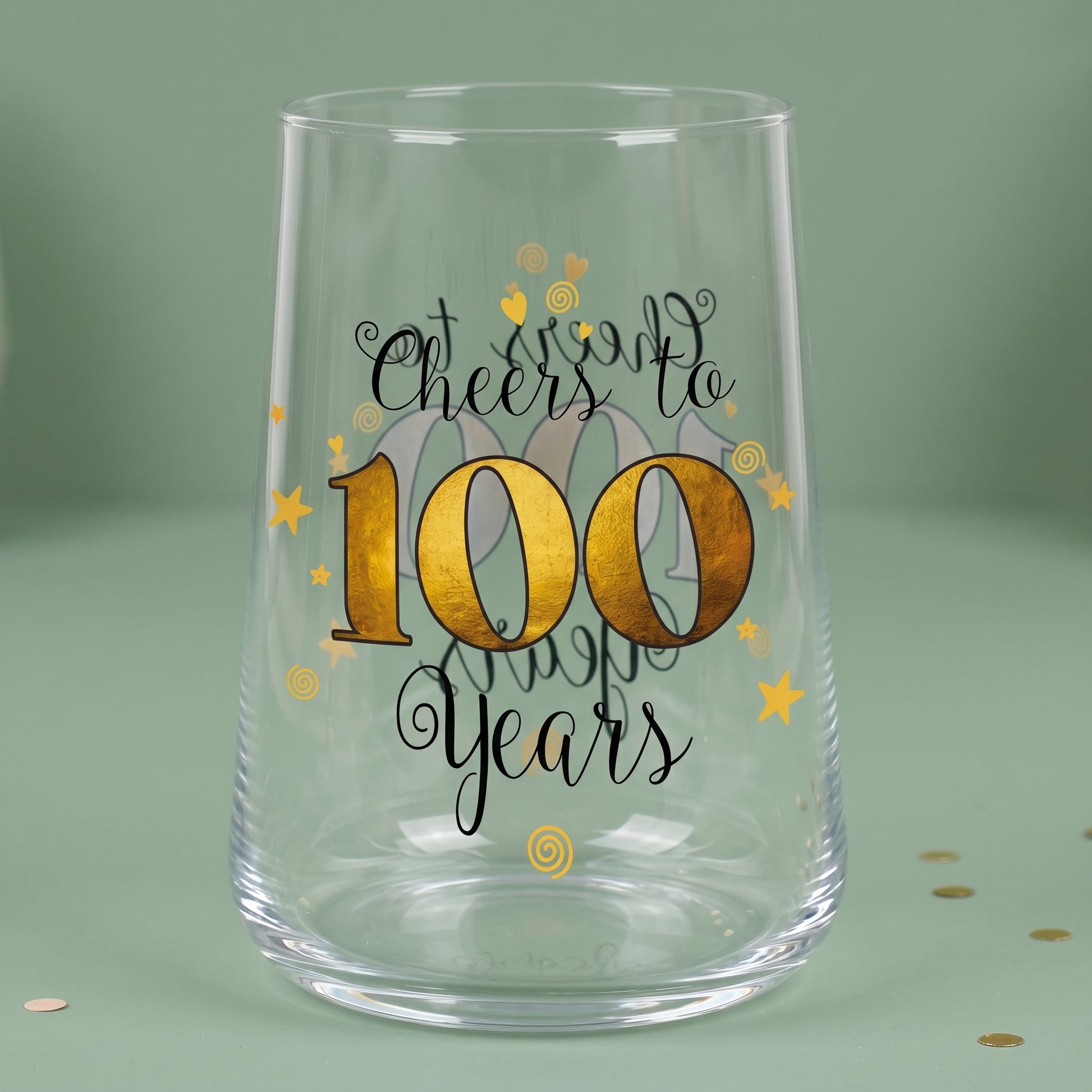 Leeres Trinkglas zum 100. Geburtstag mit goldfarbener 100 auf grünem Hintergrund