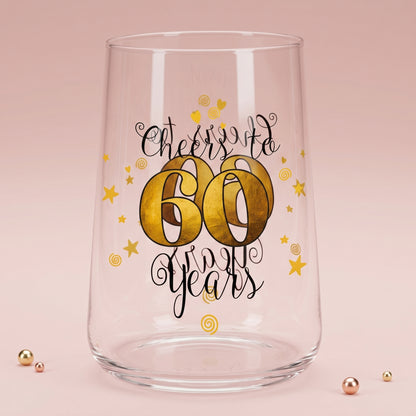 Leeres Trinkglas mit Cheers to 60 Years Aufdruck auf rosa Hintergrund