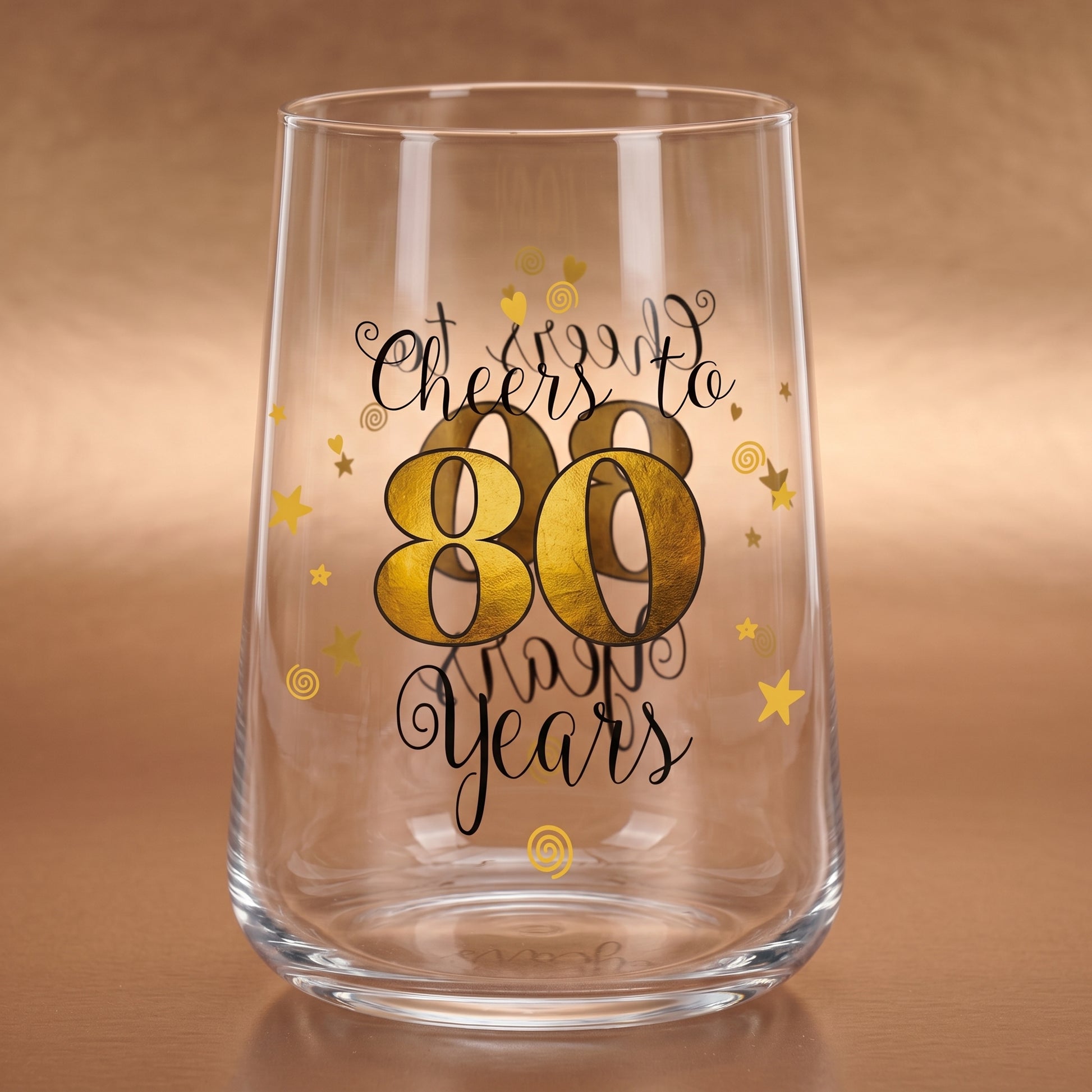 Leeres Trinkglas zum 80. Geburtstag mit goldener 80 und dekorativen Sternen auf warmem Holzuntergrund