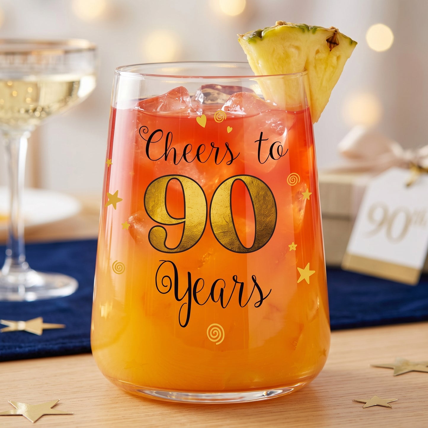 Geschenkglas zum 90. Geburtstag mit orangefarbenem Cocktail, Ananas und festlicher Dekoration