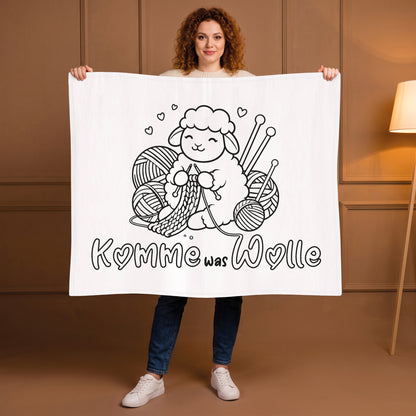 Frau hält Kuscheldecke mit Schaf beim Stricken und Spruch Komme was Wolle