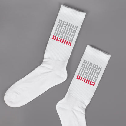 Zwei weiße Socken mit Mama Motiv nebeneinander auf grauem Hintergrund