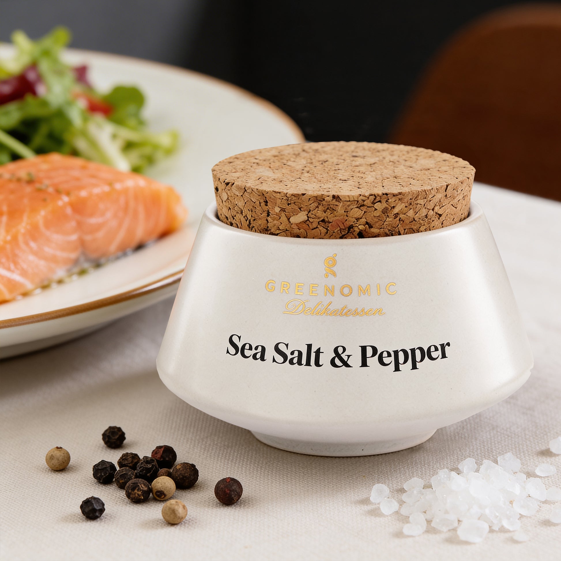 Sea Salt & Pepper im Keramiktopf neben Lachsfilet und frischem Salat angerichtet