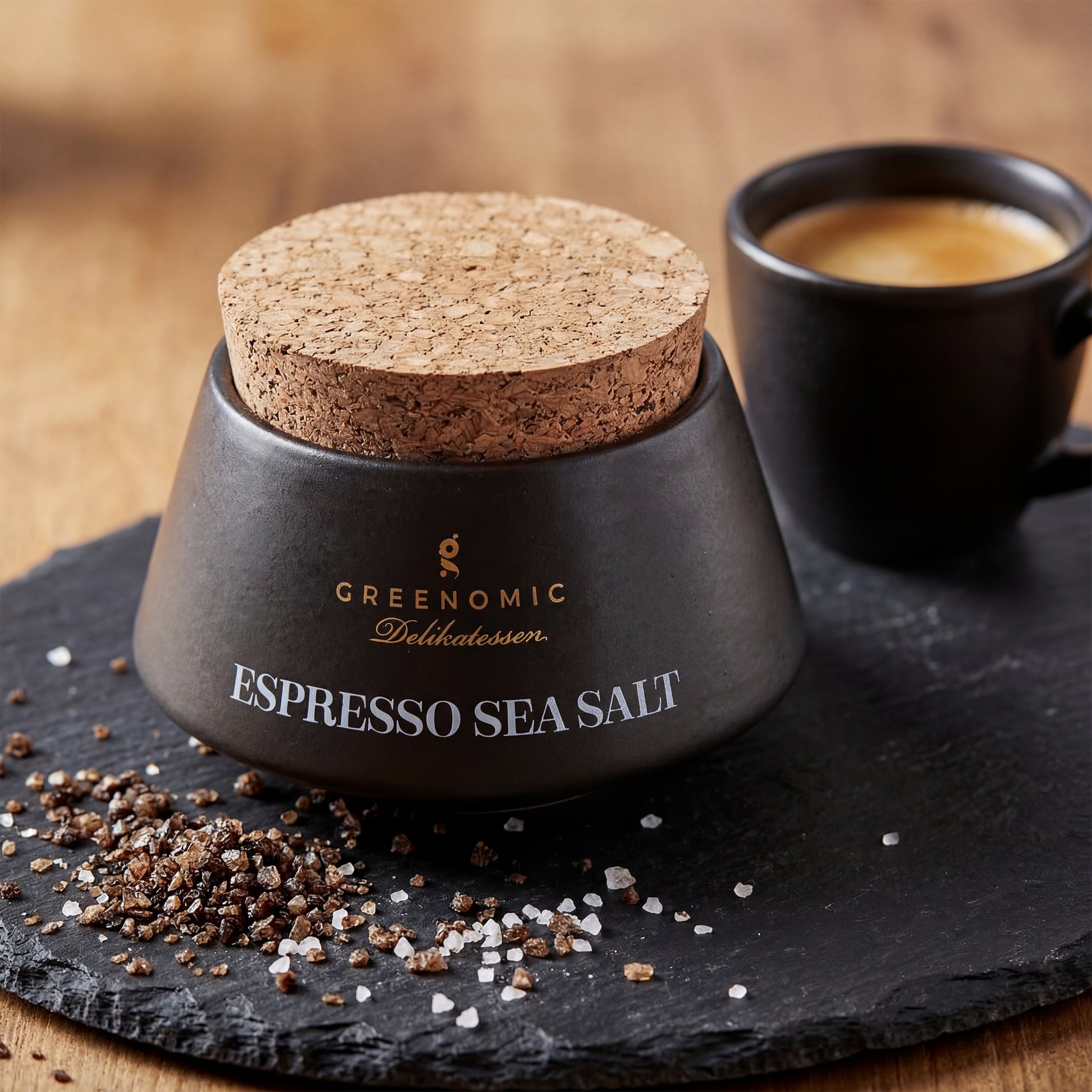Premium Meersalz mit gemahlenem Kaffee im Keramikbehälter neben Espressotasse