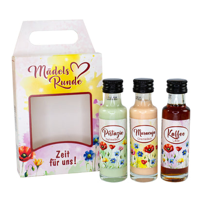 Likör Geschenkset „Mädelsrunde“ mit drei Mini-Flaschen vor Geschenkverpackung und Blumenmotiv freigestellt auf weißem Hintergrund