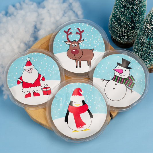 Vier runde Handwärmer mit Weihnachtsmotiven auf Holzbrett arrangiert