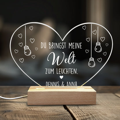 Acryl-Herzlampe mit Liebesspruch und Namen „Dennis & Anna“ auf Holzsockel, dekoriert auf Holztisch im Wohnzimmer