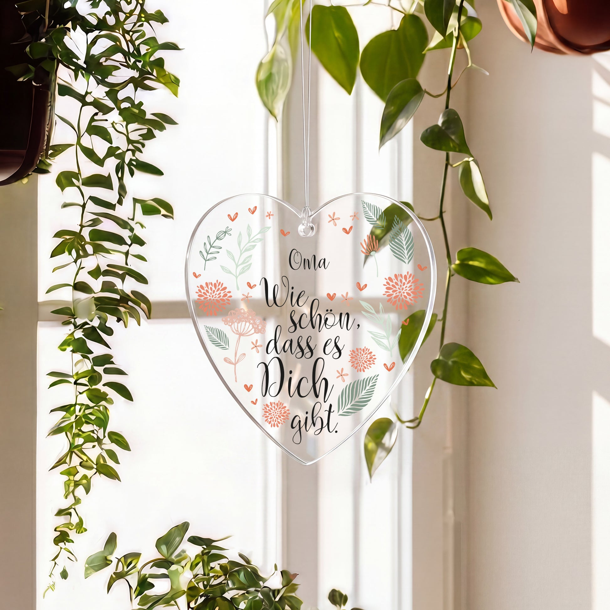 Personalisierter Acryl Herz Anhänger mit Name und floralem Motiv am Fenster aufgehängt