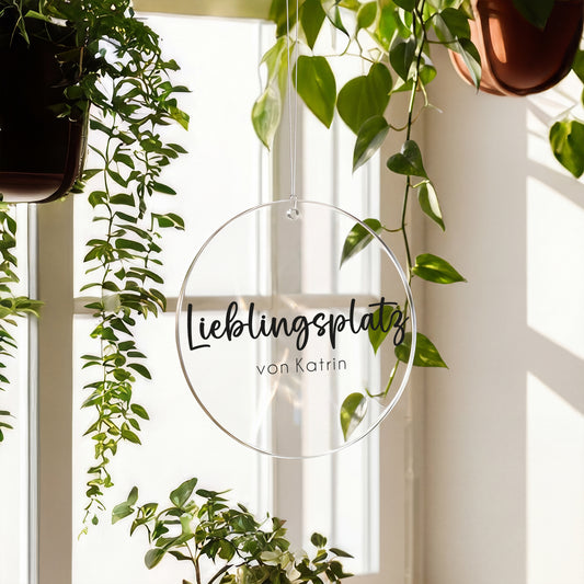 Transparenter Acrylanhänger mit Aufdruck Lieblingsplatz von Katrin am Fenster zwischen grünen Pflanzen