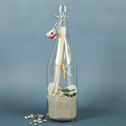 Gefüllte Flaschenpost mit Sand, Muscheln, Grün und Papier
