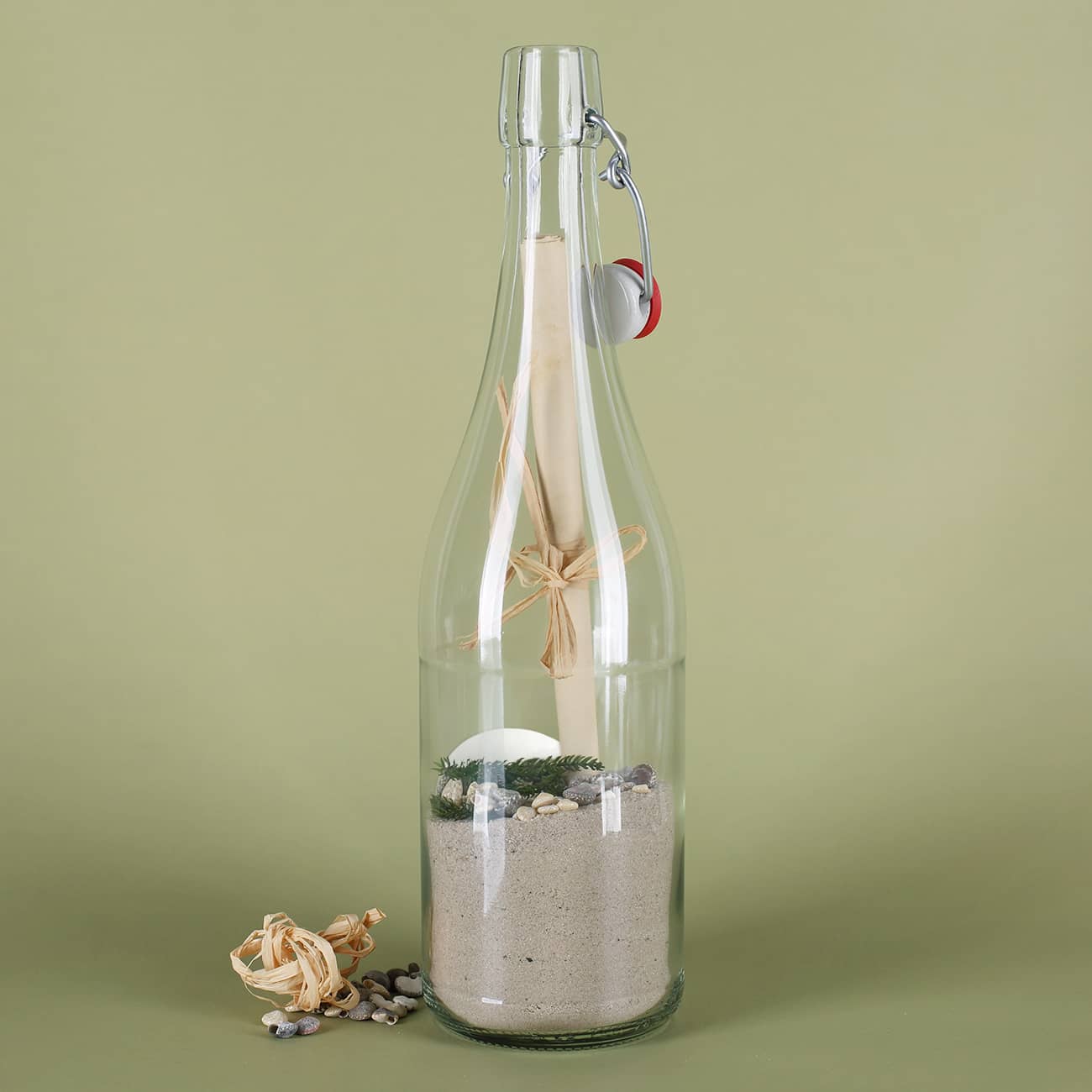 Gefüllte Flaschenpost von hinten mit Sand, Muscheln, Grün und Papier