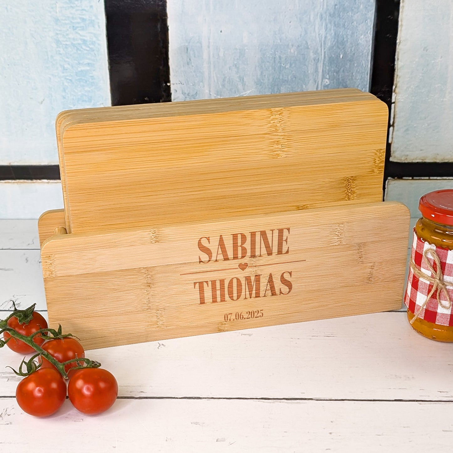 Bambusbrettchen-Set mit Gravur „Sabine & Thomas“ und Datum im Ständer auf Tisch mit Tomaten