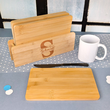 Brettchenständer mit fünf Bambusbrettchen, graviert mit Initiale „S“ und dem Namen „Schmidt“, daneben Messer und weiße Tasse.