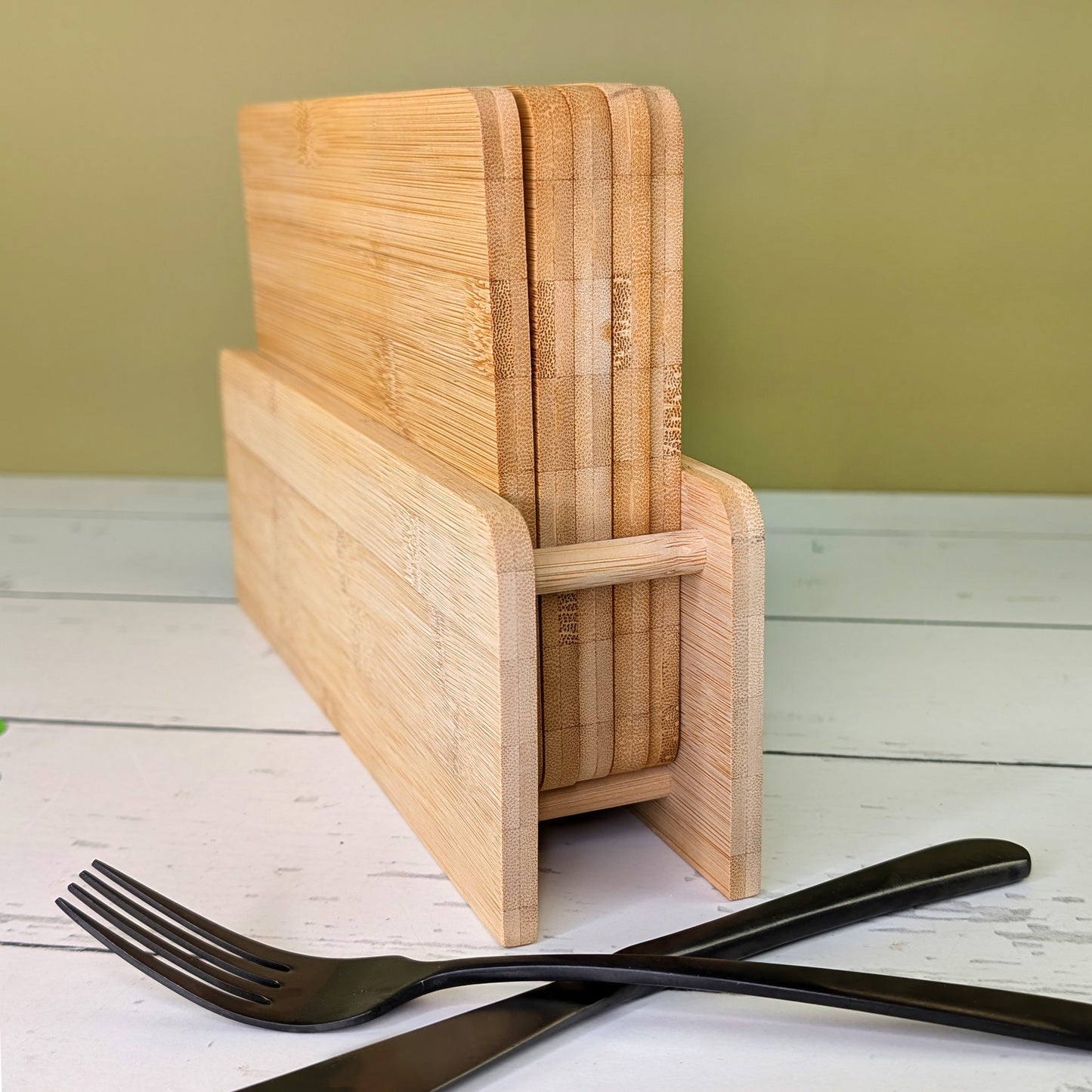 Rückansicht des Bambus-Brettchenständers mit fünf Brettchen, auf Tisch mit Besteck