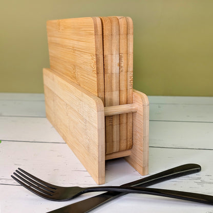 Rückansicht des Bambus-Brettchenständers mit fünf Brettchen, auf Tisch mit Besteck